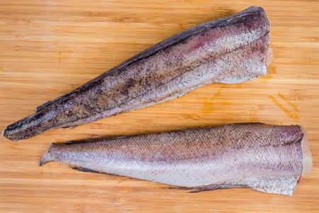 Uncooked carcasses of the hake on a wooden surface
