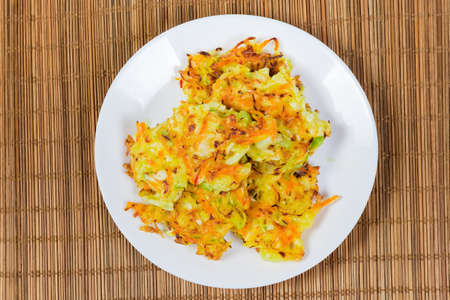 Fried savory cabbage pancakes on white dish on the bamboo table mat, top viewの写真素材