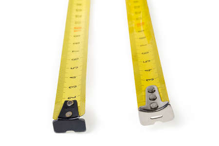 Flexible metal rulers with metric scales of two self-retracting tape measures close-up in selective focus on a white backgroundの写真素材