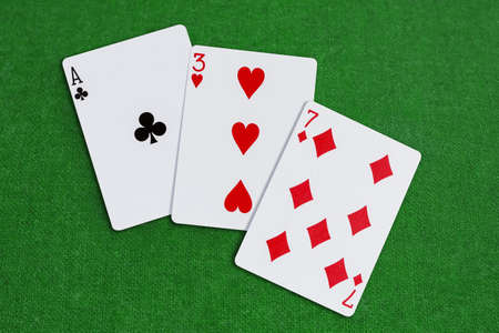Three, Seven, Ace combination of playing cards laid out on the table covered with green baizeの写真素材