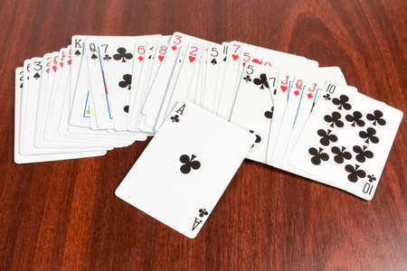 Deck of french playing cards with standard English pattern scattered face-up and ace of clubs on top...