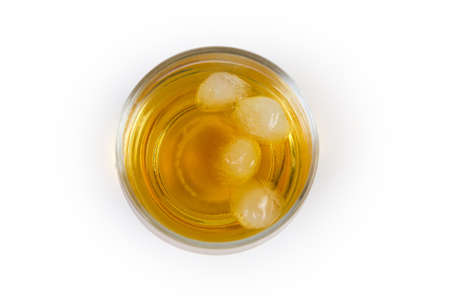 Glass of whisky with pieces of ice on a white background, top view