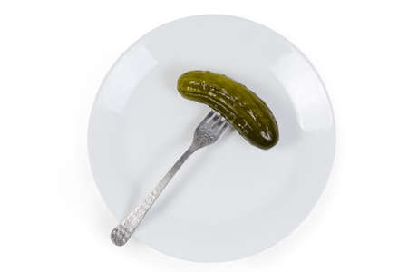 Canned cucumber on the fork lies on white dish on a white background, top viewの写真素材