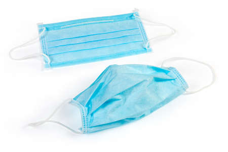 Two light blue disposable medical face three-ply masks with metal wire for securely cover nose on a...