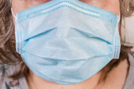 Light blue disposable medical three-ply mask with metal wire for securely cover nose dressed on face...