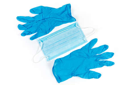 Blue disposable medical face mask and pair of nitrile powder free medical gloves on a white...