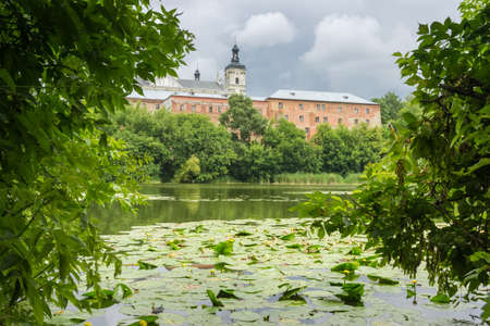 Former fortified Monastery of the Order of Discalced Carmelites of the 17th century. View of southwestern part with water and trees on a foreground in cloudy weather, Berdychiv, Ukraineの写真素材