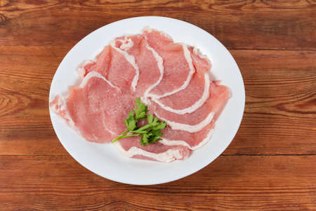 Uncooked tenderized boneless slices of pork loin for chops preparation on the dish on the rustic tableの写真素材