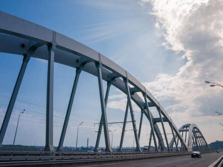 Steel riveted arches of the combined road and railroad bridge against the sky with clouds, fragmentの写真素材