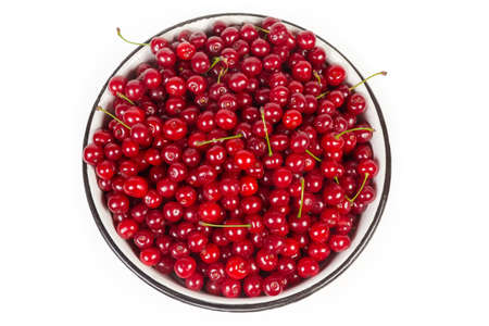 Freshly picked sour cherries in big enameled bowl on a white background, top view, background
