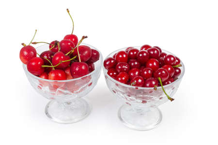 Fresh sour cherries and sweet cherries in the two glass cups on a white backgroundの写真素材