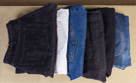 Different pairs of jeans various colors and textures, folded back pockets up on a textile surface ,...