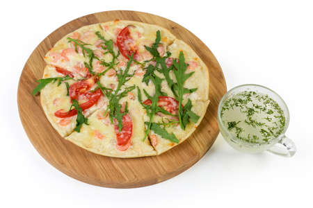 Small cooked pizza with shrimps, tomatoes and arugula on the round wooden oaken pizza board and...