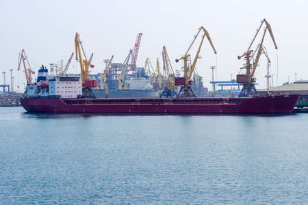 Part of the sea cargo port with different harbor cranes, dry cargo ship and part of the water area...