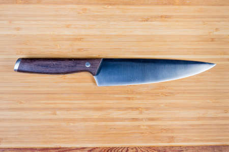 Kitchen stainless steel large chef's knife on the wooden bamboo cutting board