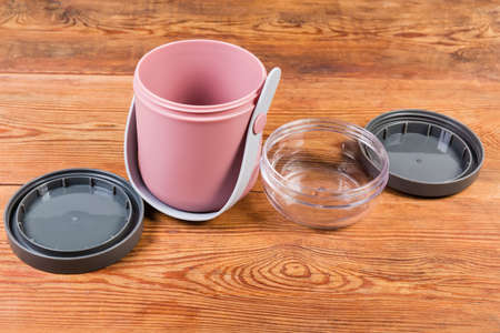 Disassembled empty plastic lunch box with two pots with removed lids on the old rustic table