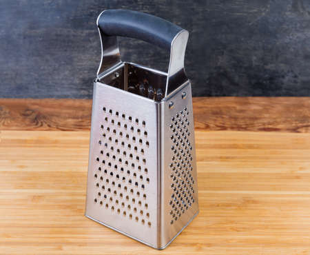 Stainless steel kitchen box-shaped grater with four various grating surfaces and ergonomic handle on...