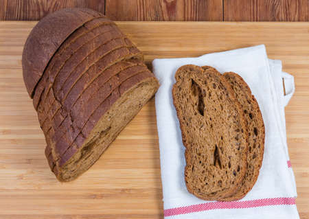 Sliced hearth loaf of brown bread made with wheat and rye flour, slices bread on napkin  on the...