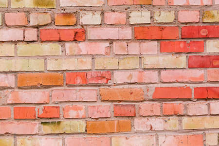 Fragment of the old wall built of red and yellow bricks with cracks and spots. Texture, background