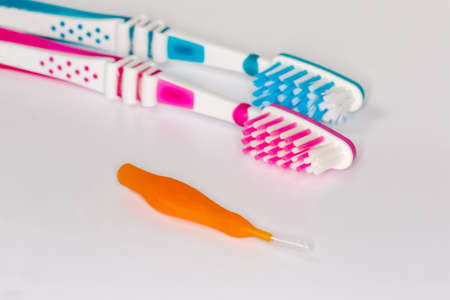 Straight interdental brush on a blurred background of usual toothbrushes on a light surface, close-up in selective focusの写真素材