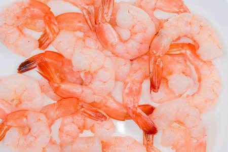 Cooked tails of prawns peeled from the shells with unpeeled tips on the white dish, fragment close-upの写真素材