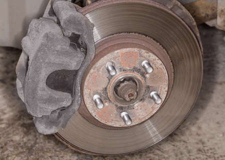 Front wheel hub with ventilated disc brake assembly and five studs on an used car, view close-up...