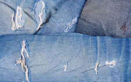 Hole and worn places in the different old torn jeans showing the frayed threads and fabric texture,...