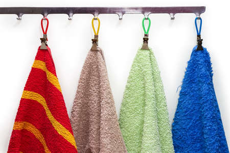 Various terry bath towels different colors with clothespins hanging on the hanger hooks on a white background, fragmentの写真素材