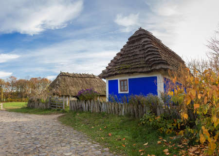 Old Ukrainian rural house with blue decoranive pattern of walls and thatched roof built in the 19th century, autumn day. Pyrohiv, Kyiv, Ukraineの写真素材