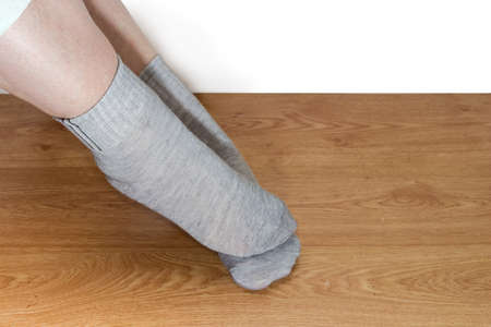 Gray socks on the legs of woman against a wooden floor close-up on a white background