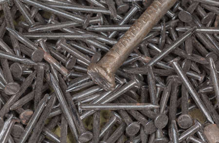 Pile of the small thin steel nails and upper part of a big nail on a foreground, top view close-up...
