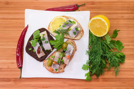 Different open sandwiches made with slices of pickled Atlantic herring fillet and various  bread...