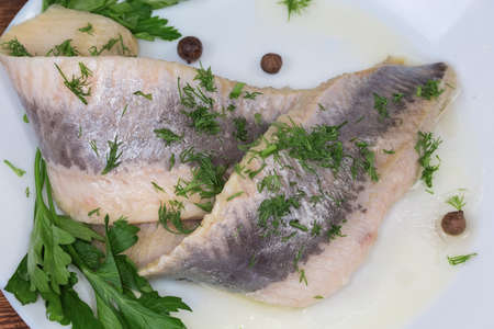 Pickled mild salted herring fillets without skin sprinkled with chopped dill on dish with parsley...