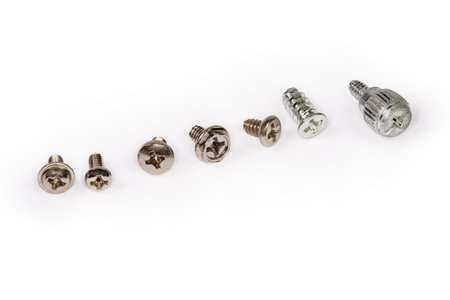 Different self-threading sheet metal screws and machine screw with cross recessed and combined heads and anti corrosion coating lined in a row on a white surface close-upの写真素材