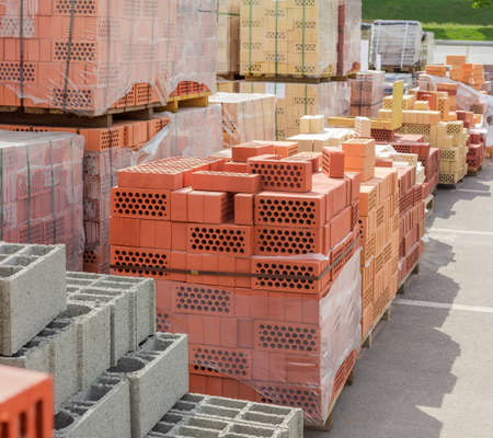 Different building bricks and other construction materials stacked on the wooden pallets on an outdoor warehouseの写真素材