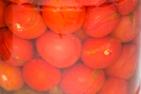 Canned cherry tomatoes in glass jar, view of fragment close-up through the glassの写真素材