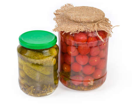 Canned cucumbers and cherry tomatoes with spices in two glass jars different sizes on a white backgroundの写真素材