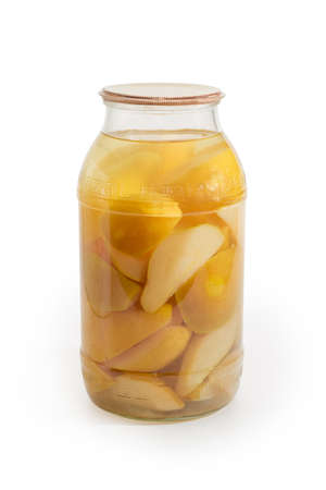 Canned slices of pears in syrup in glass jar on a white backgroundの写真素材