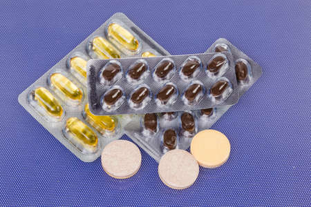 Effervescent tablets, different capsules in blister packing on blue surface