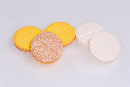 Different effervescent tablets of pharmaceutical product on a white surface, close-up in selective...