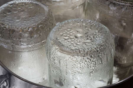 Glass jars in the stainless steel pot during steam sterilization for the home canning, fragment close-upの写真素材