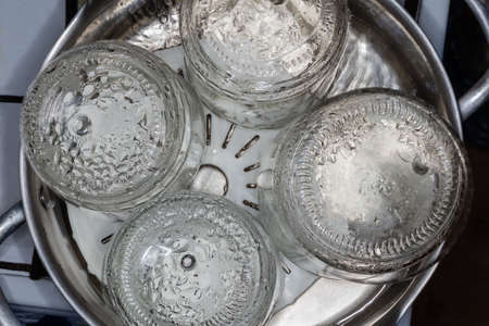 Glass jars in the stainless steel pot over the steamer during steam sterilization for the home canning, top viewの写真素材