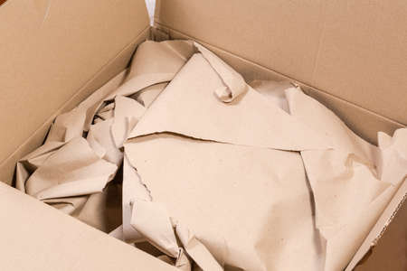 Open rectangular packing box made with kraft corrugated fiberboard with slightly crumpled wrapping...