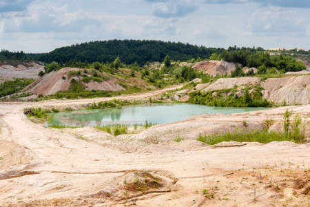 Small quarry lake with turquoise water in abandoned former china clay quarry in summer day