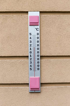 Large outdoor thermometer with Celsius scale, attached to the facade concrete building in classic...