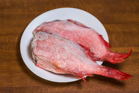 Frozen headless gutted carcasses of redfish also known as ocean perch, covered with hoarfrost on...
