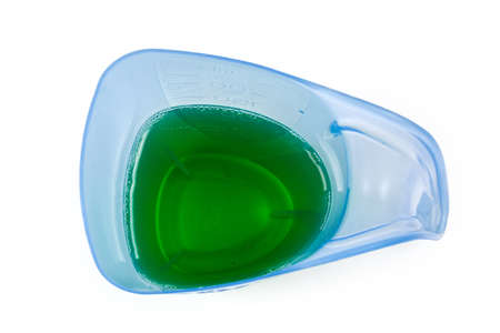 Blue transparent plastic measuring cup with green liquid laundry detergent on a white background, top viewの写真素材