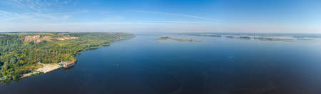 Wide river with a forested steep one coast and a flat other, numerous islands in the middle in autumn, wide panoramic aerial view above the waterの写真素材
