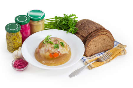 Pork jelly in the glass bowl, different seasoning, brown bread and fork on napkin on a white...