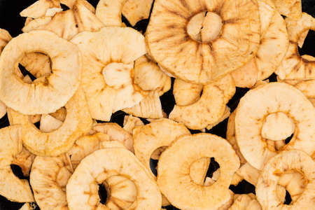 Pile of baked thin apple chips on the black dish, top view close-up, backgroundの写真素材
